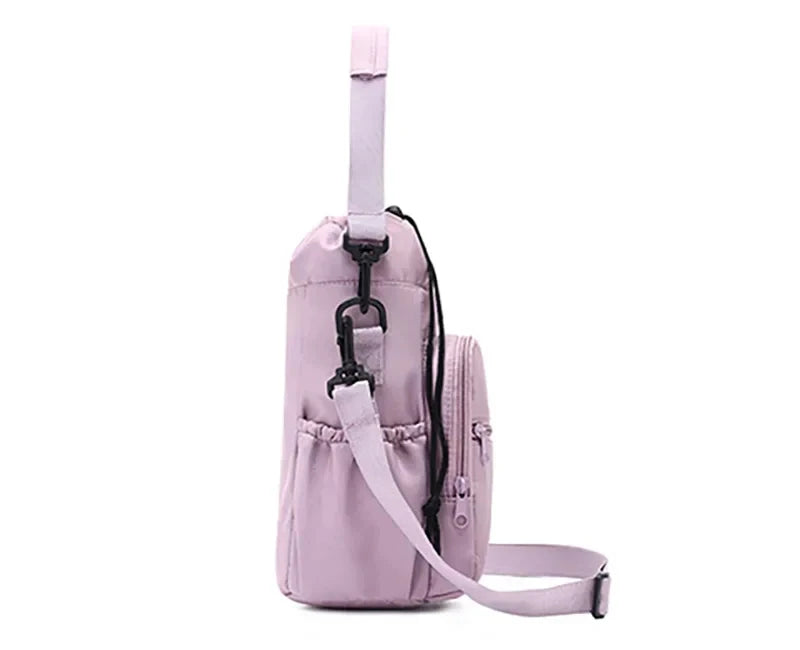 Side view of light purple CarrySling bag showing side mesh pocket, clip attachment, and adjustable strap