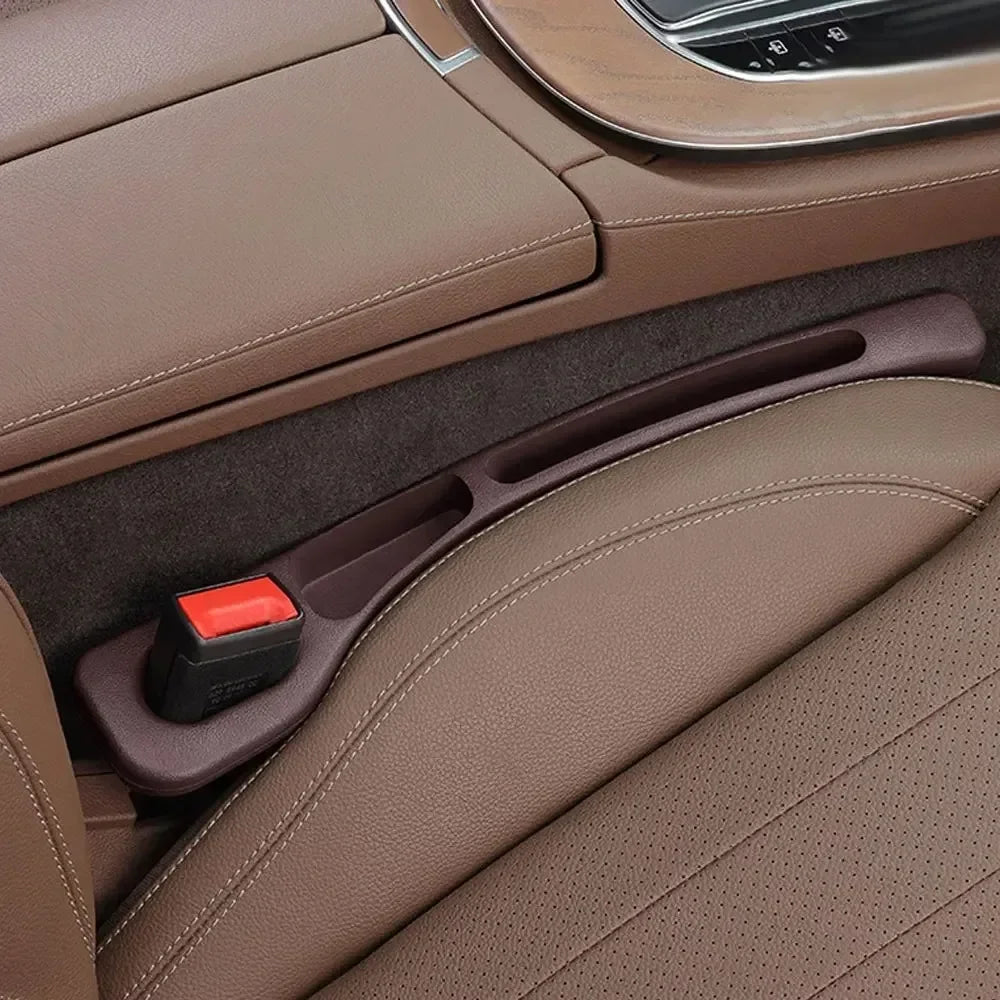 GapGuard dark brown seat gap filler installed in tan leather car seat, close-up of red seatbelt buckle