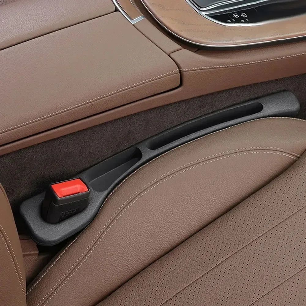 GapGuard black seat gap filler installed in brown leather car seat, close-up of red seatbelt buckle